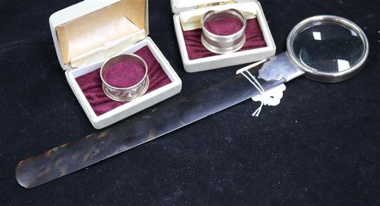 A George V silver mounted tortoiseshell page turner with magnifying glass terminal and two cased silver napkin rings.